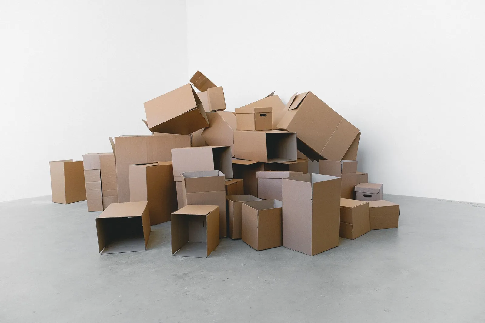 A pile of empty cardboard boxes stacked on the floor of a bare room