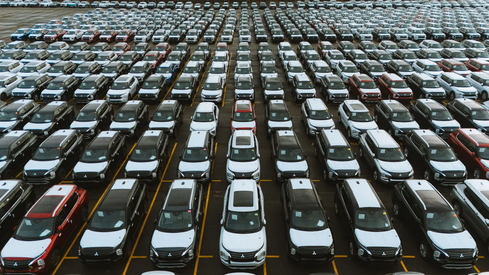 Row of new cars parked at a dealership lot under daylight