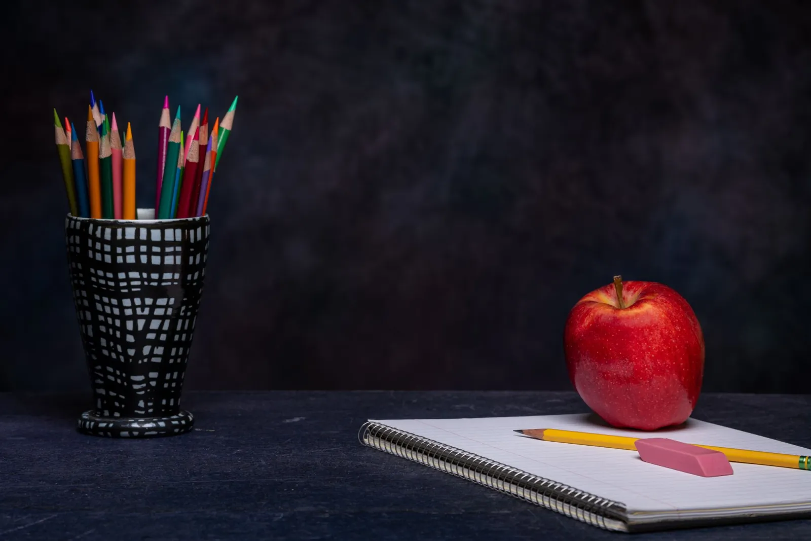 Notebook and colored pencils arranged on a wooden desk