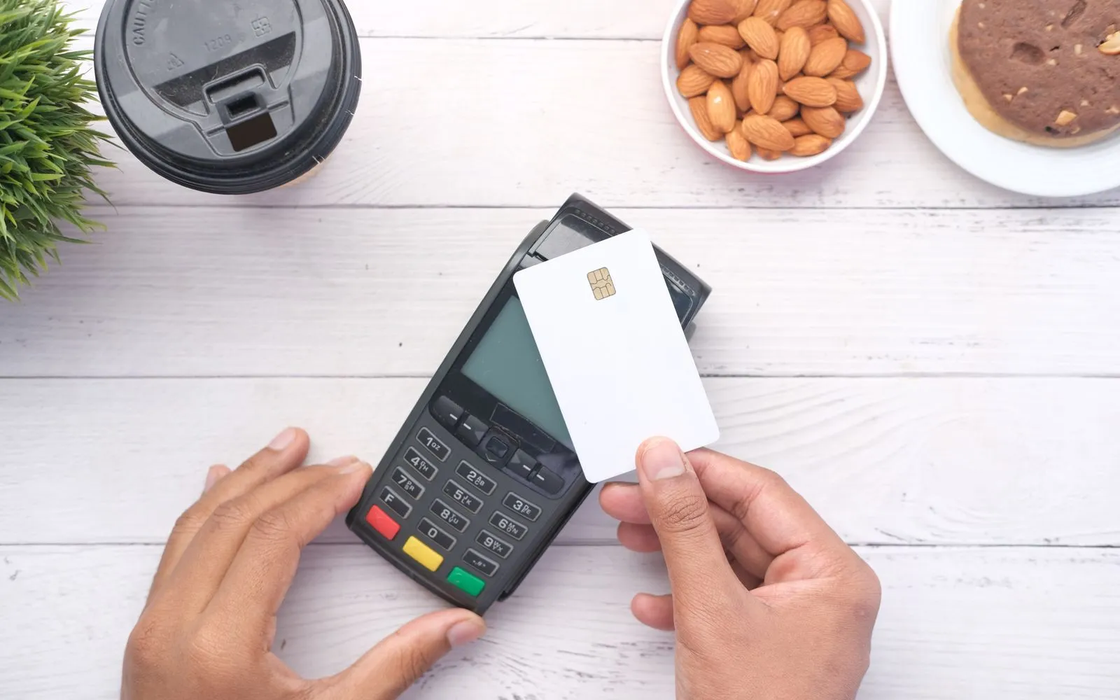 Person paying at a coffee shop counter with a physical credit card