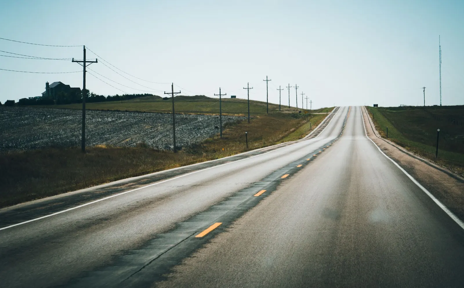 Two-lane highway running past farmland under an overcast sky