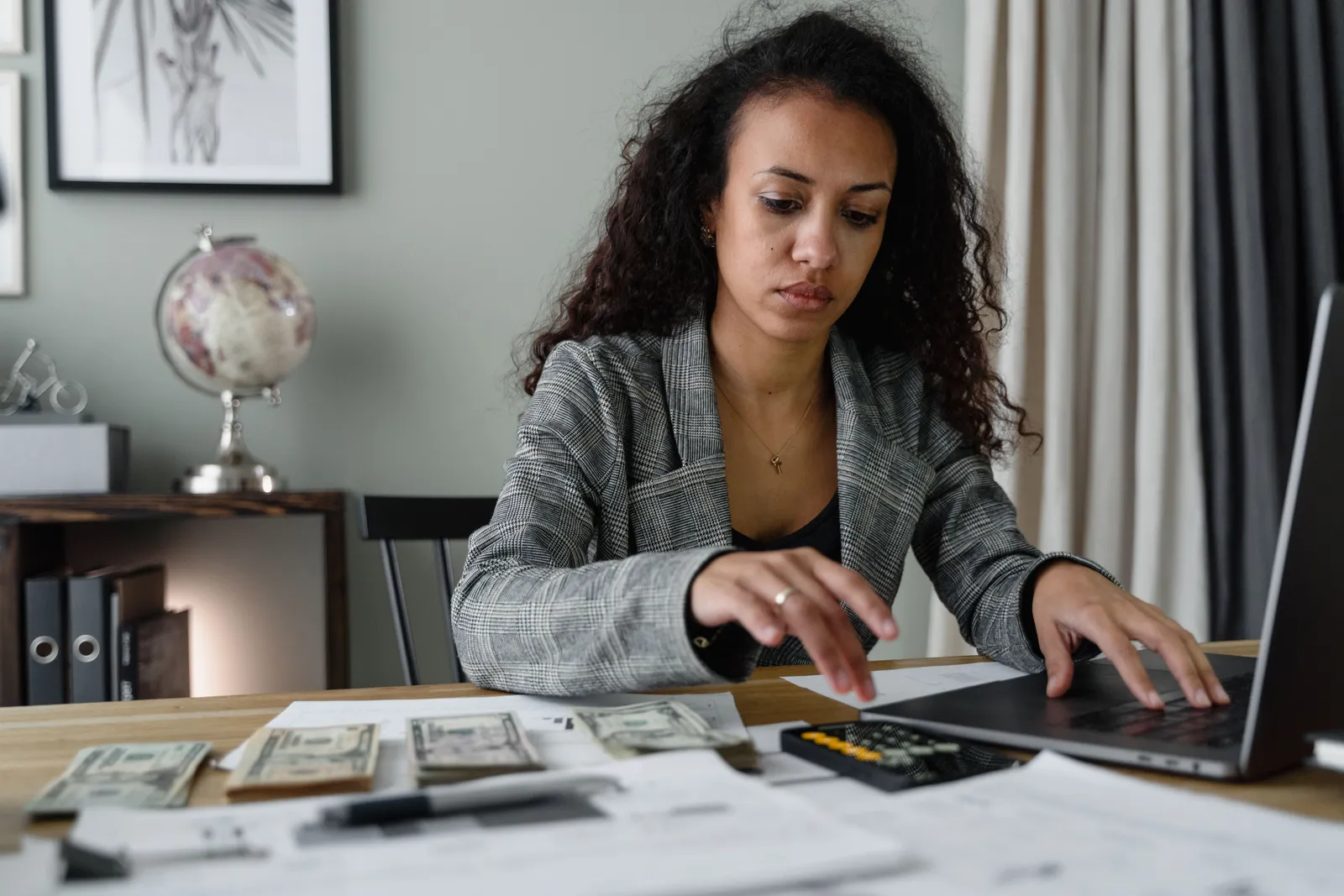 A person checking their phone next to a laptop showing a personal finance dashboard