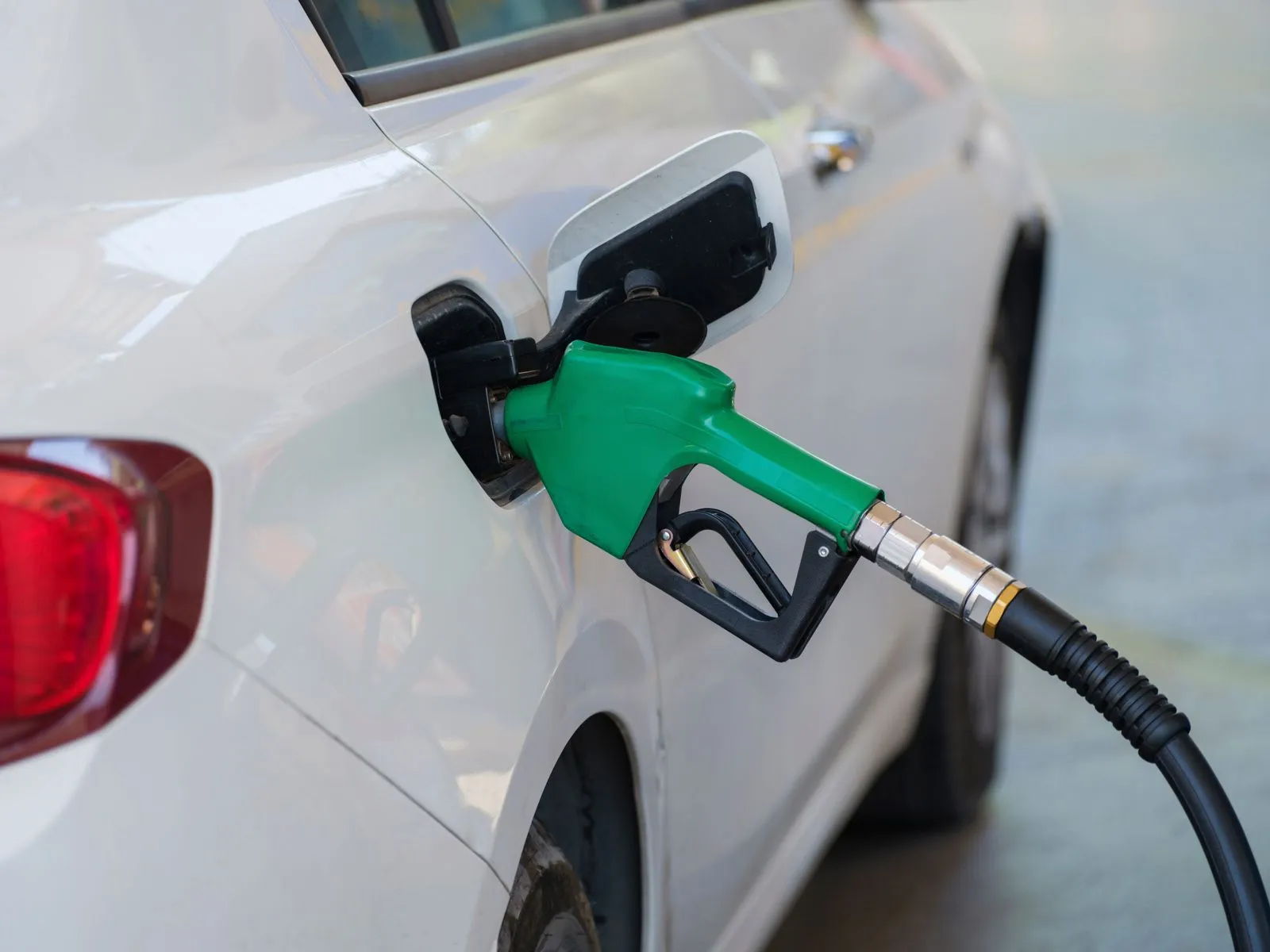 A person filling up a car at a gas station on a summer afternoon
