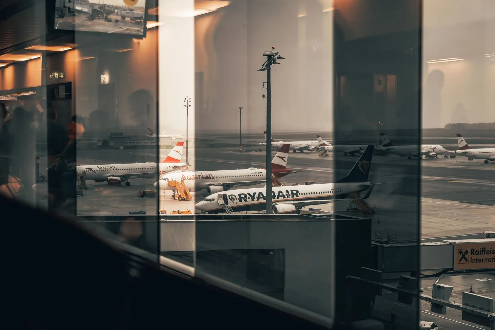 Traveler at an airport gate window watching aircraft with a boarding pass