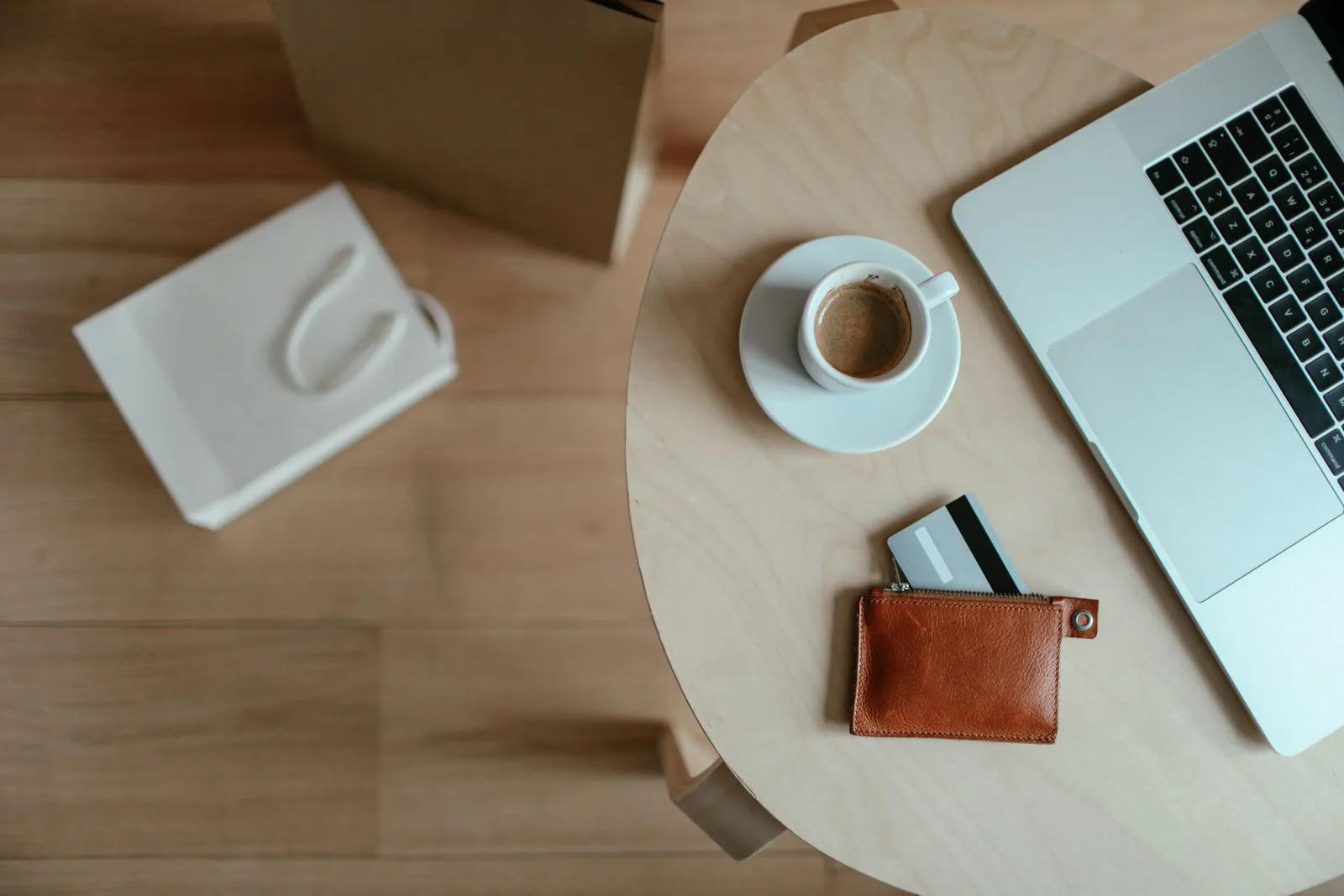 Minimalist desk with a laptop, coffee cup, and open leather wallet with a card