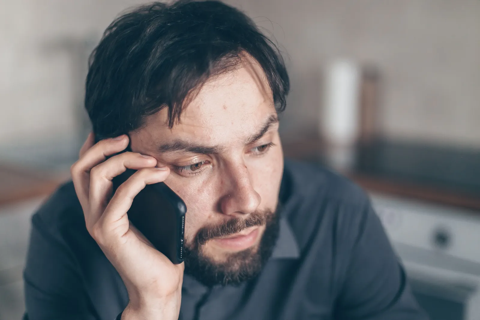 Tired man holding a phone to his ear and looking away