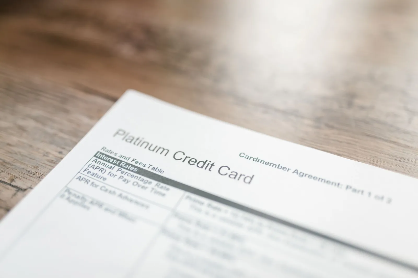 A printed credit card agreement showing an interest rate table on a wooden desk