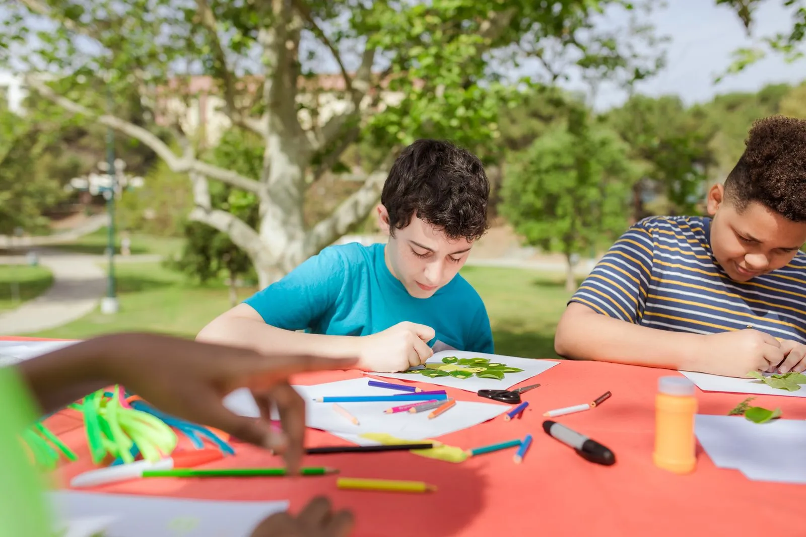 Kids doing arts and crafts at a summer camp table under trees