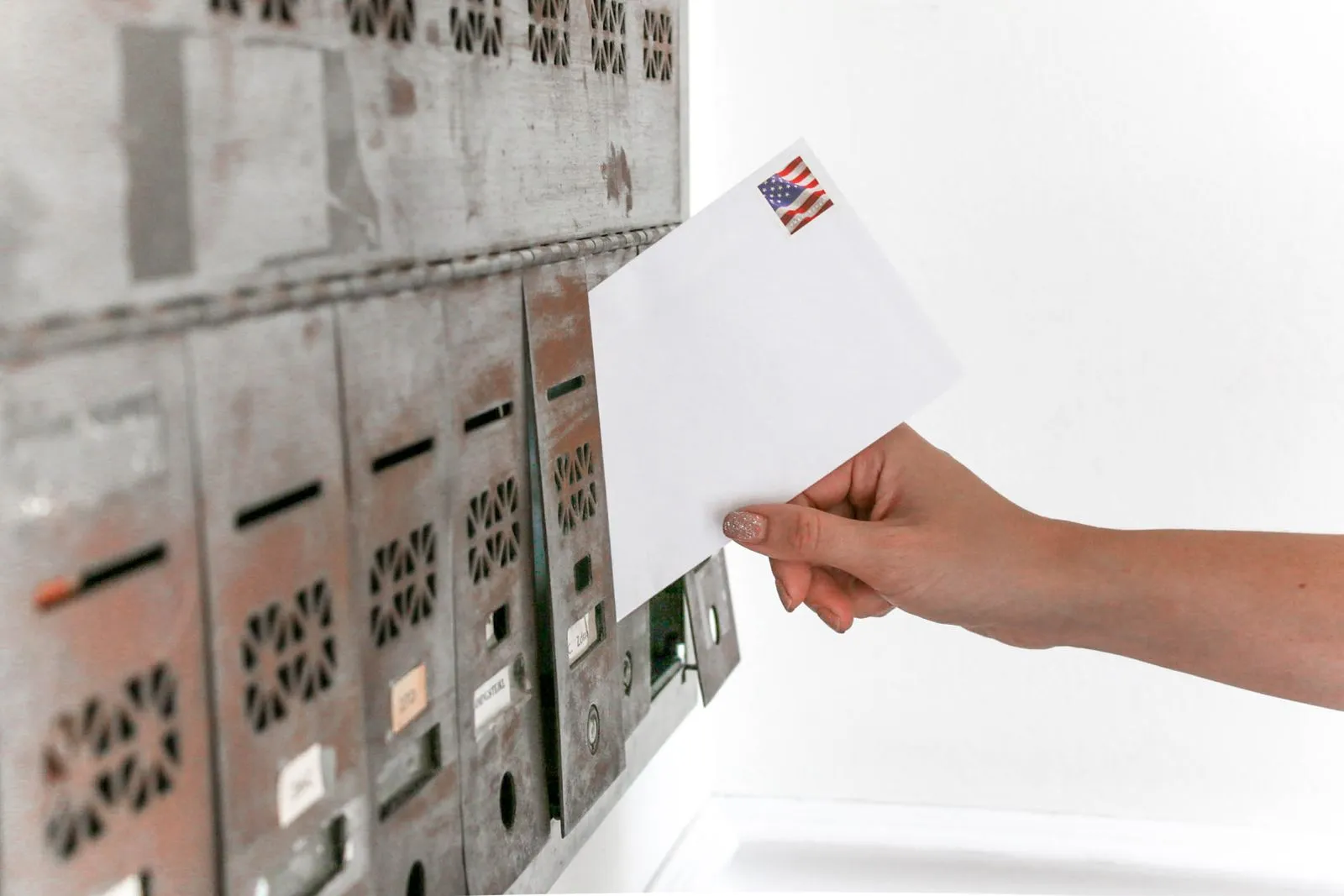 A person holding a plain white envelope over a wooden desk