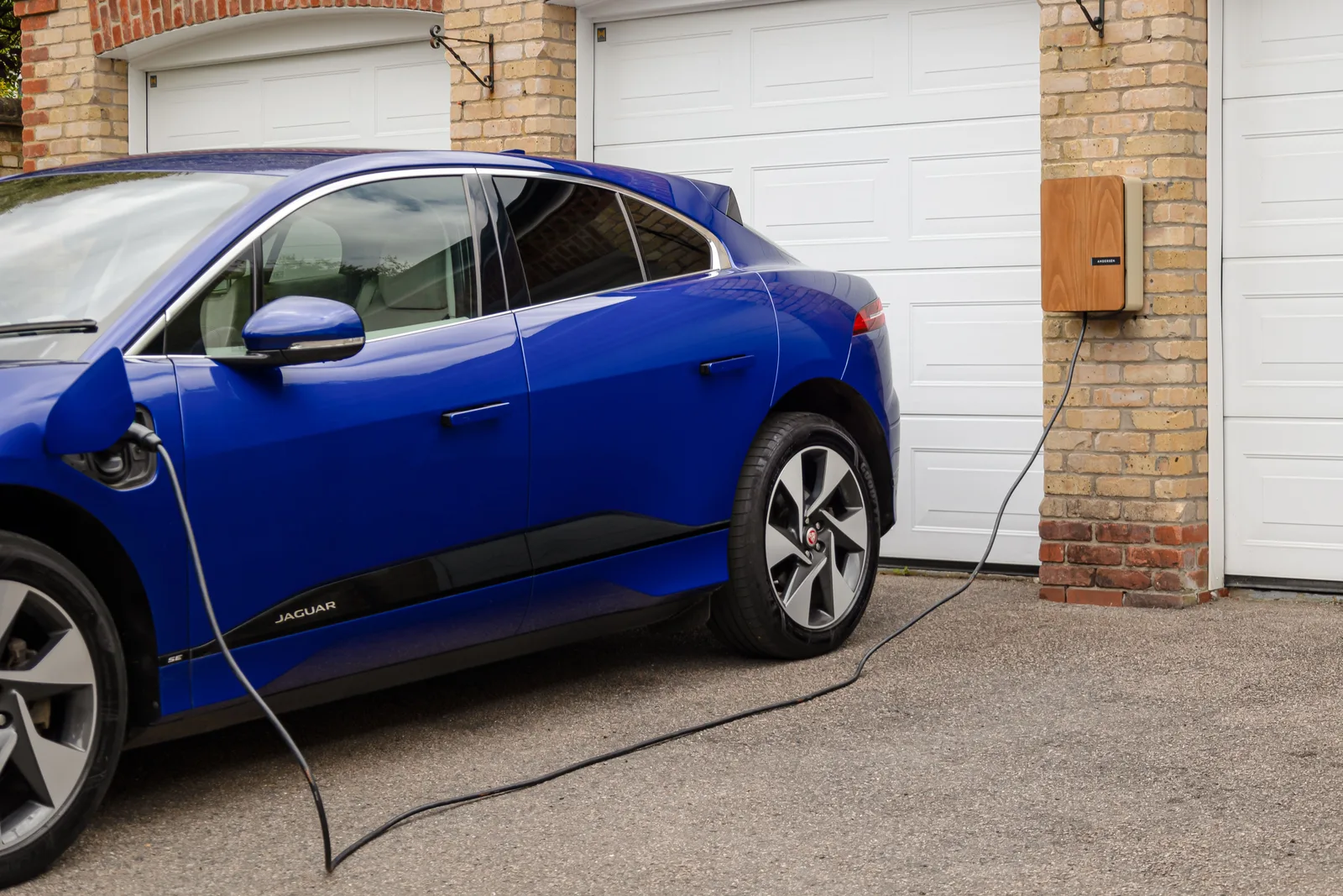 Electric vehicle plugged into a Level 2 home charger mounted on a garage wall