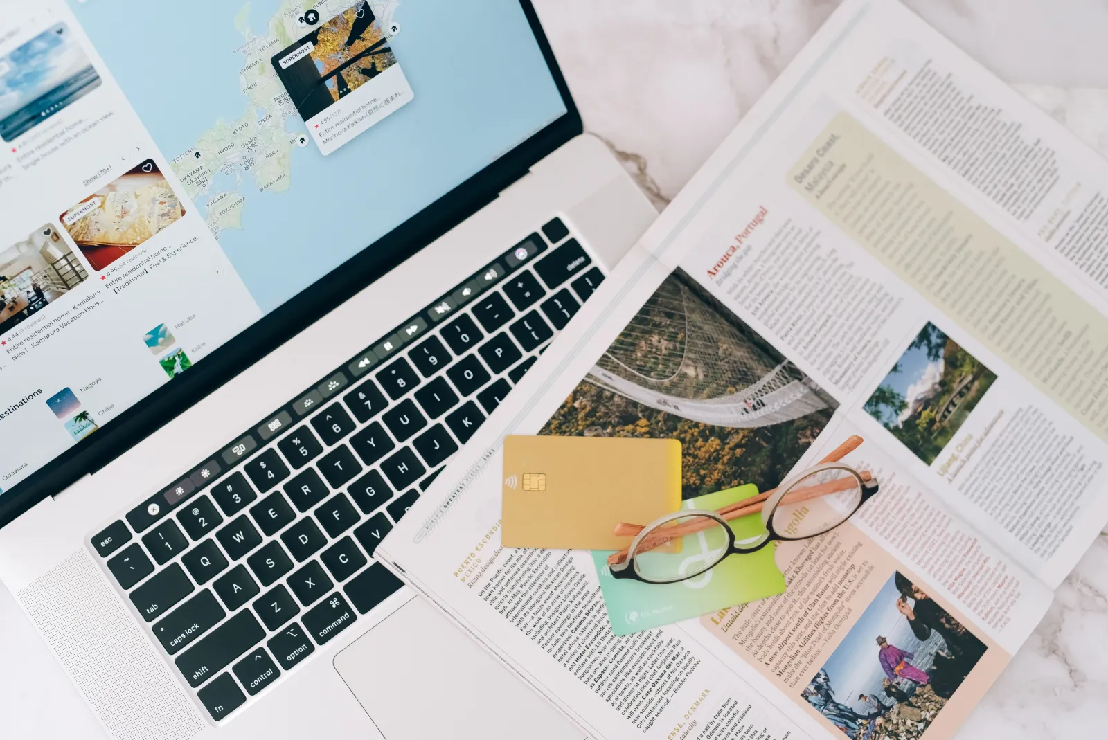 Overhead view of a laptop, world map, and credit cards on a wooden desk