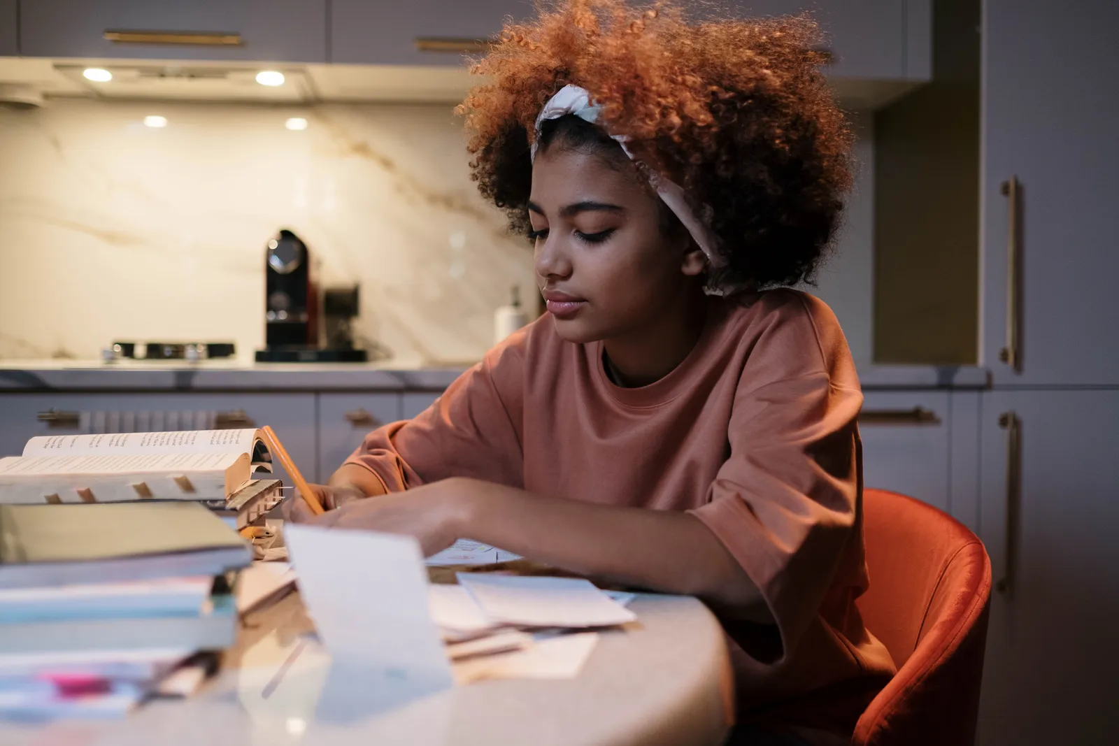 Student working through books and paperwork at a kitchen table