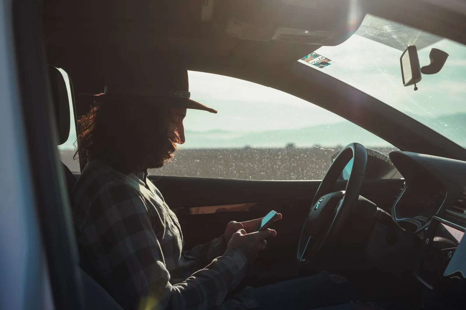 A driver sitting in a parked car checking something on a phone