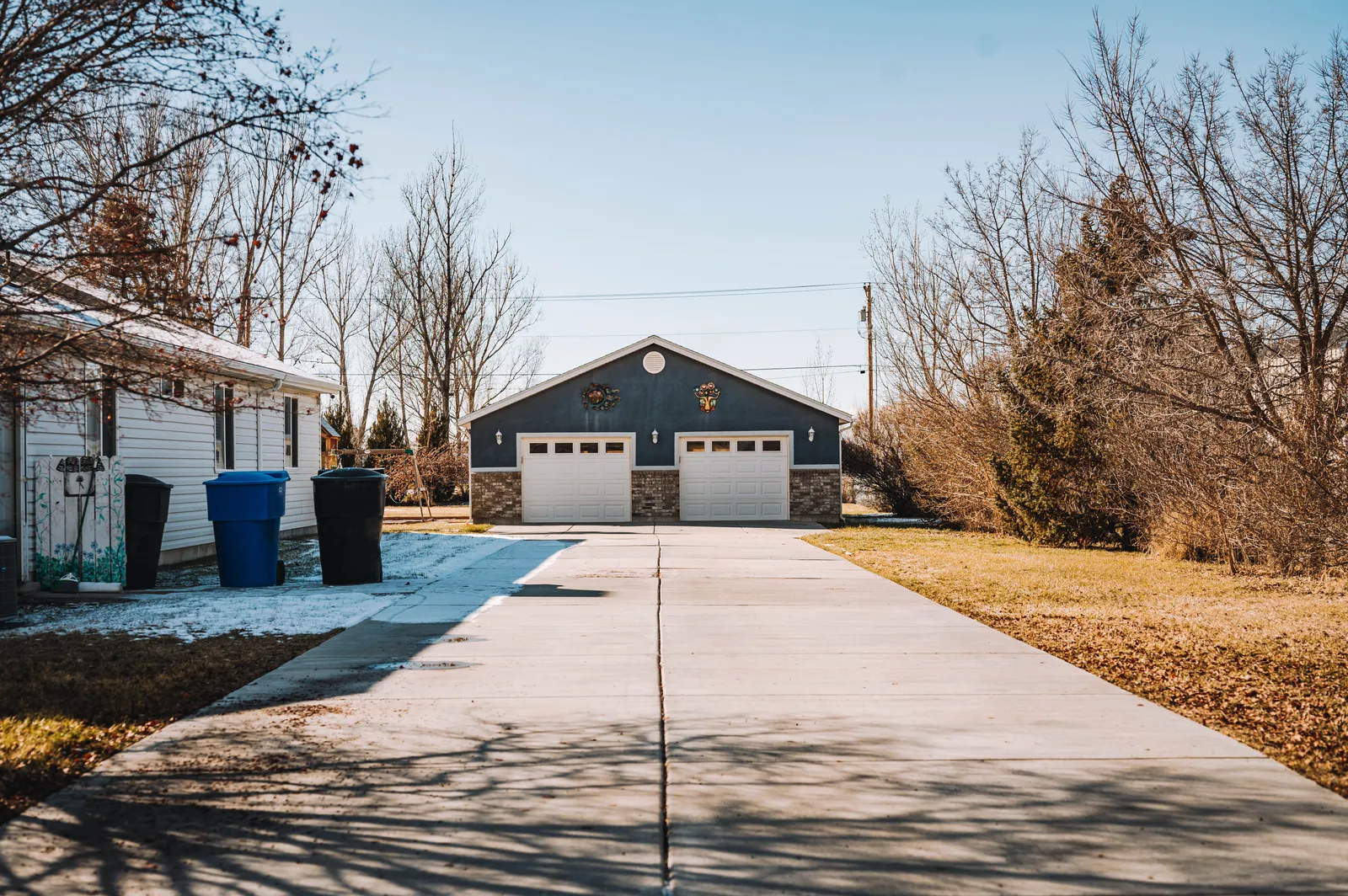An empty concrete driveway leading to a closed two-car garage on a clear winter day