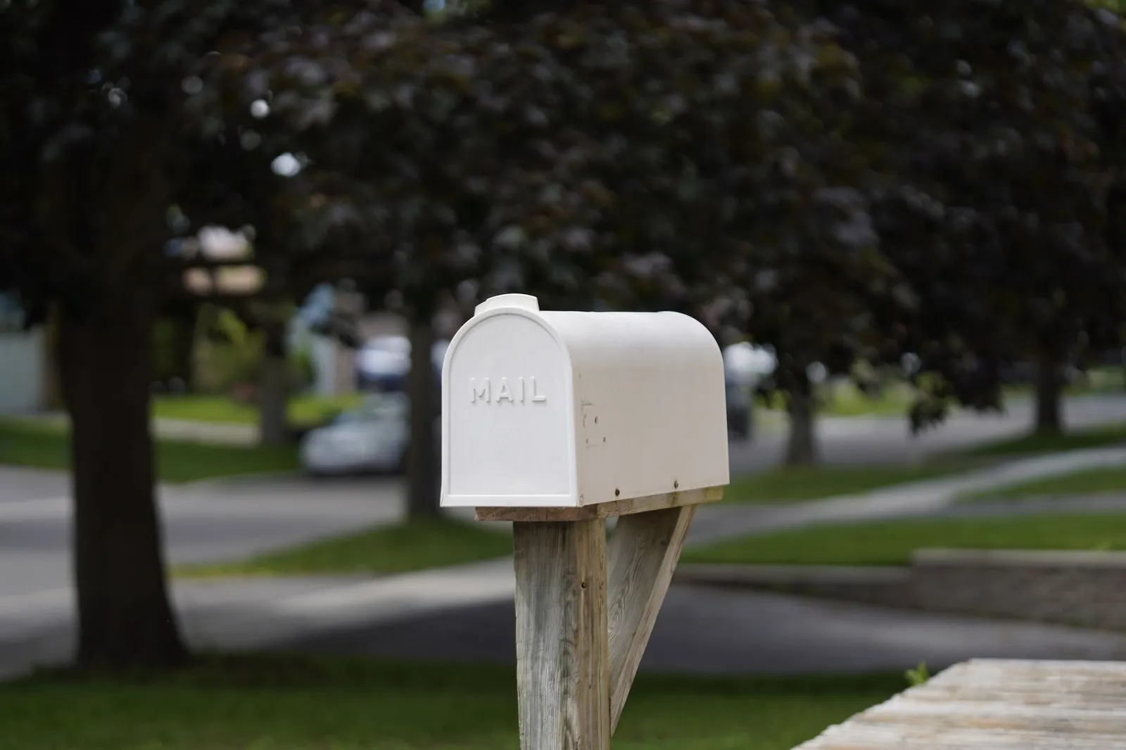 A white residential mailbox on a suburban street in daylight