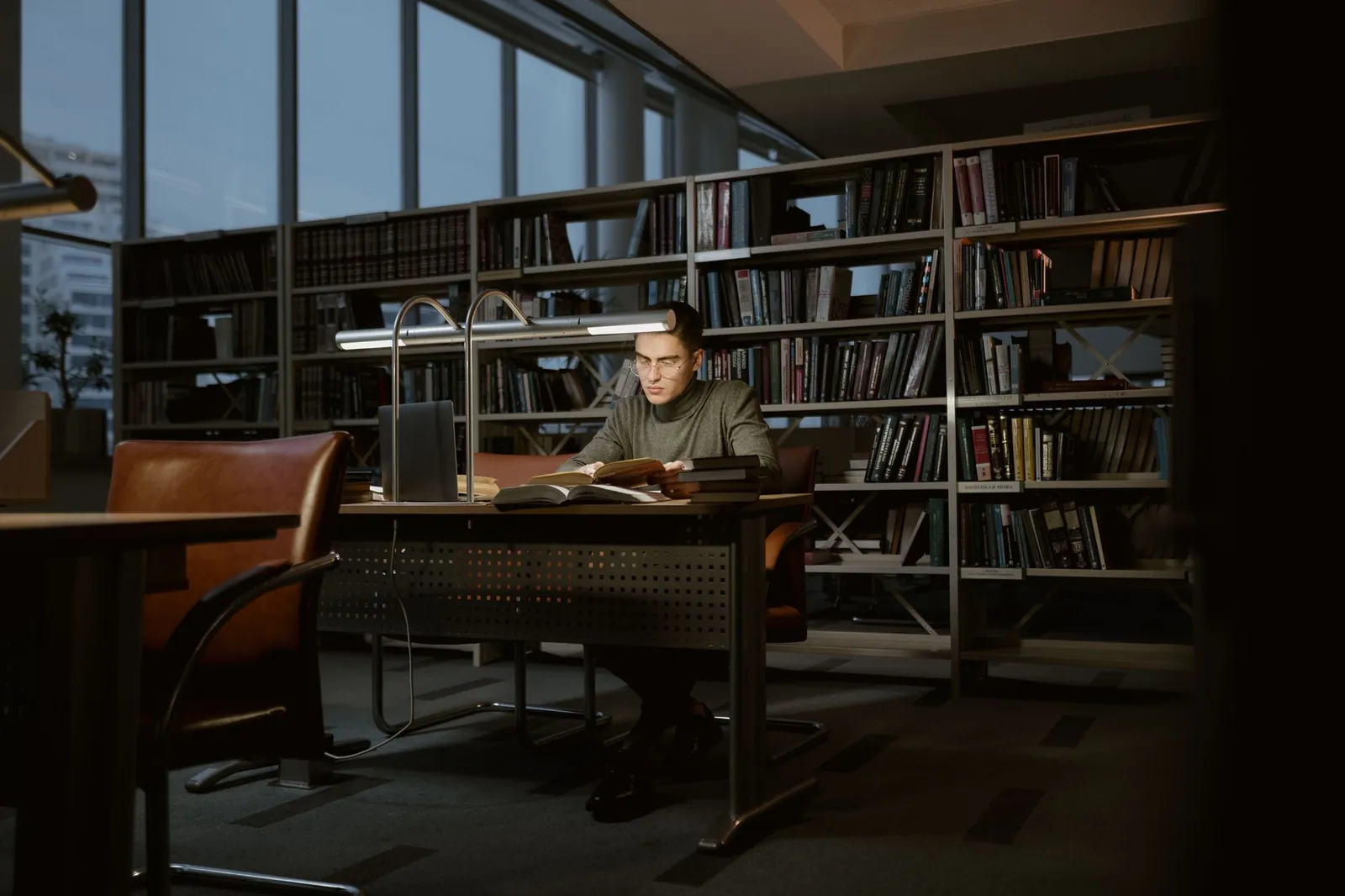 Graduate student studying with a laptop and notebook in a library