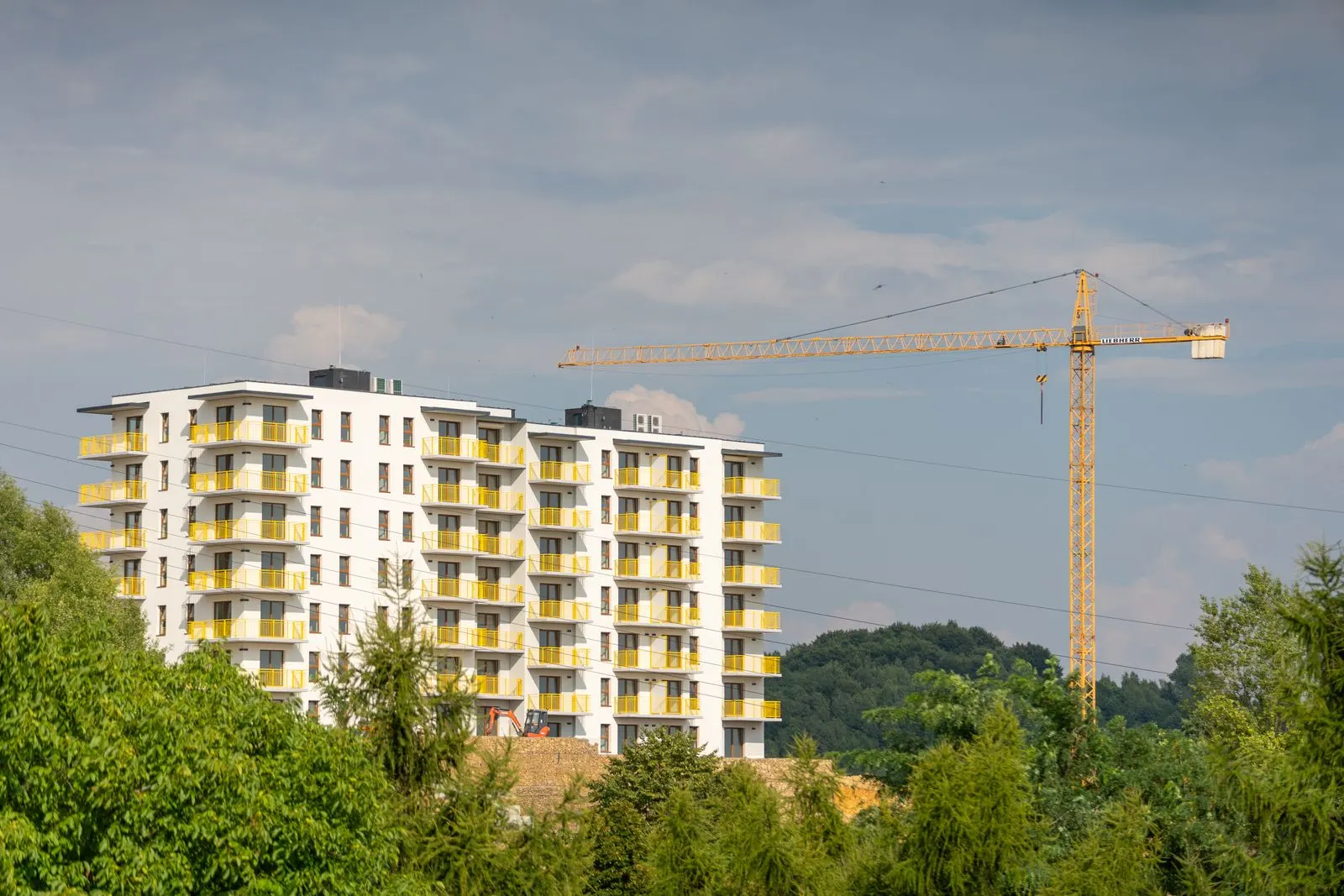 Apartment building under construction with a tower crane against a clear sky