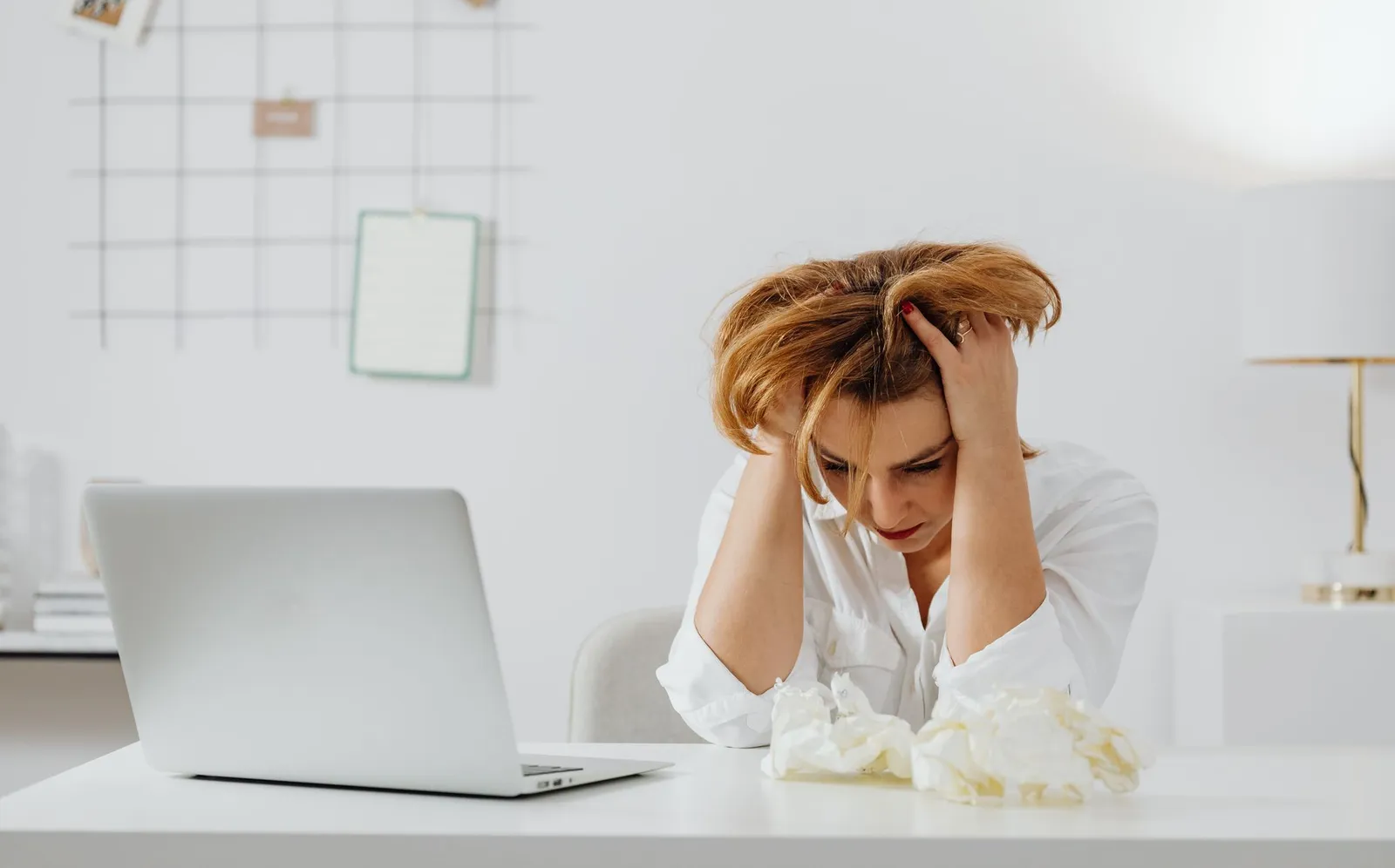 Woman at a desk looking stressed while working on a laptop