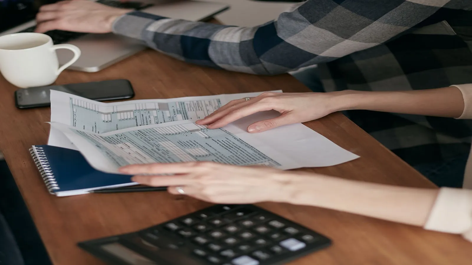 Person opening a paper letter from the IRS at a small table by a window