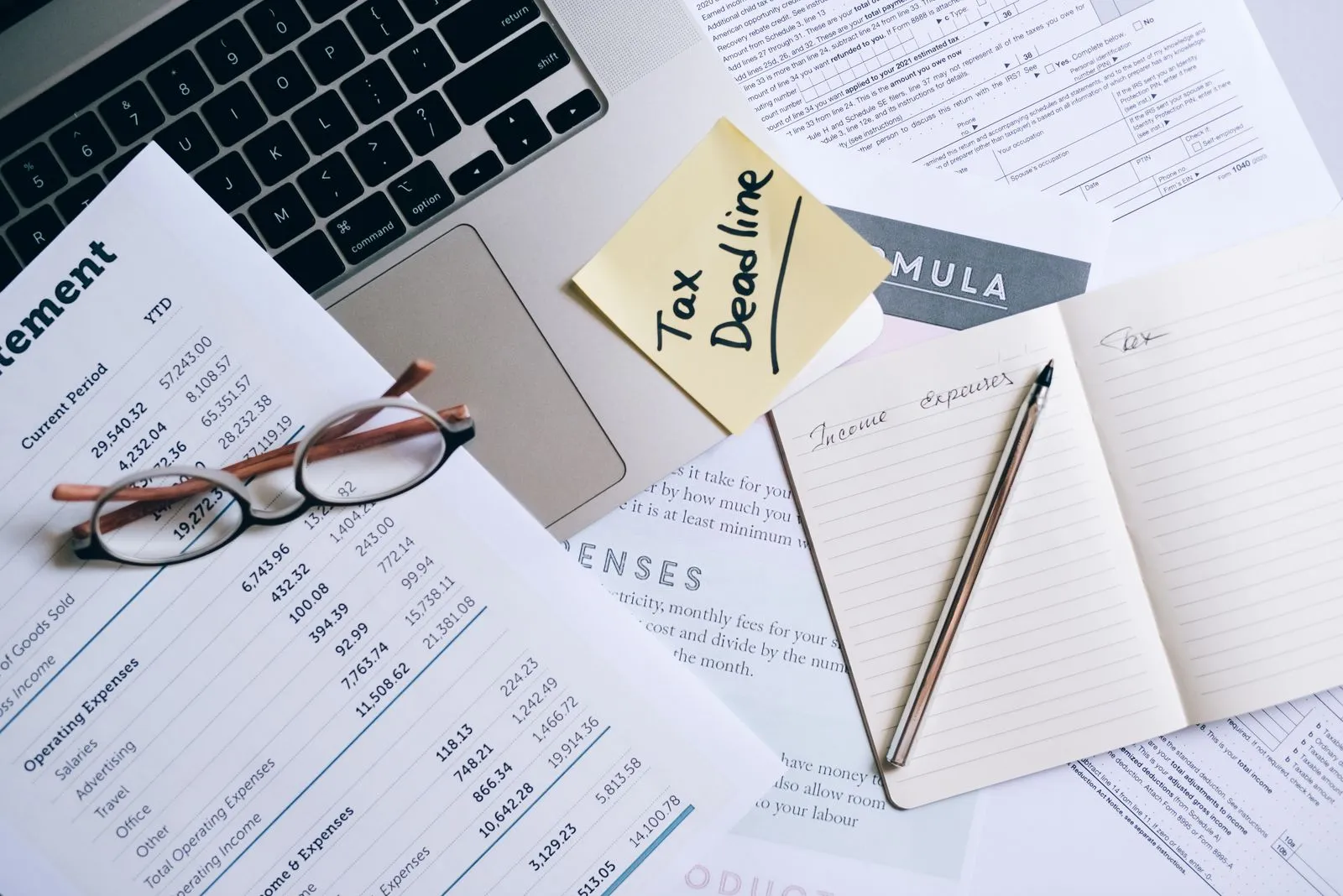 Person reviewing tax documents at a kitchen table with a laptop