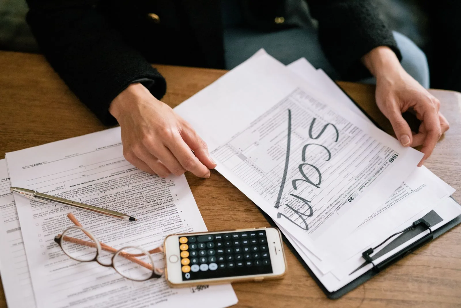 Person holding a paper tax form at a wooden table