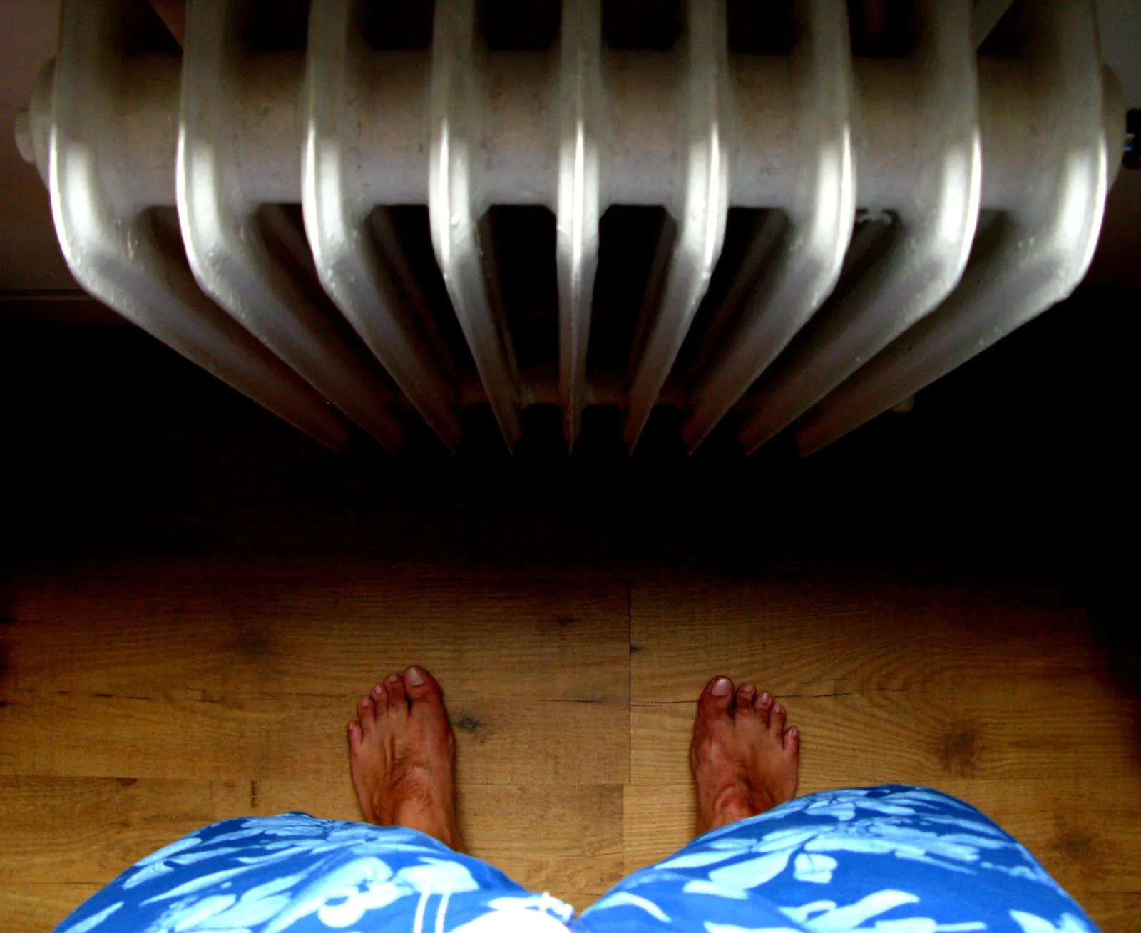 Bare feet on a wooden floor in front of an old cast iron radiator