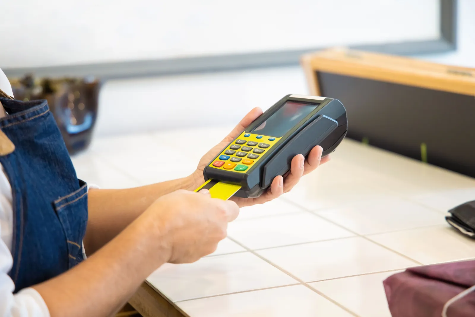 Hands inserting a payment card into a card reader at a shop counter