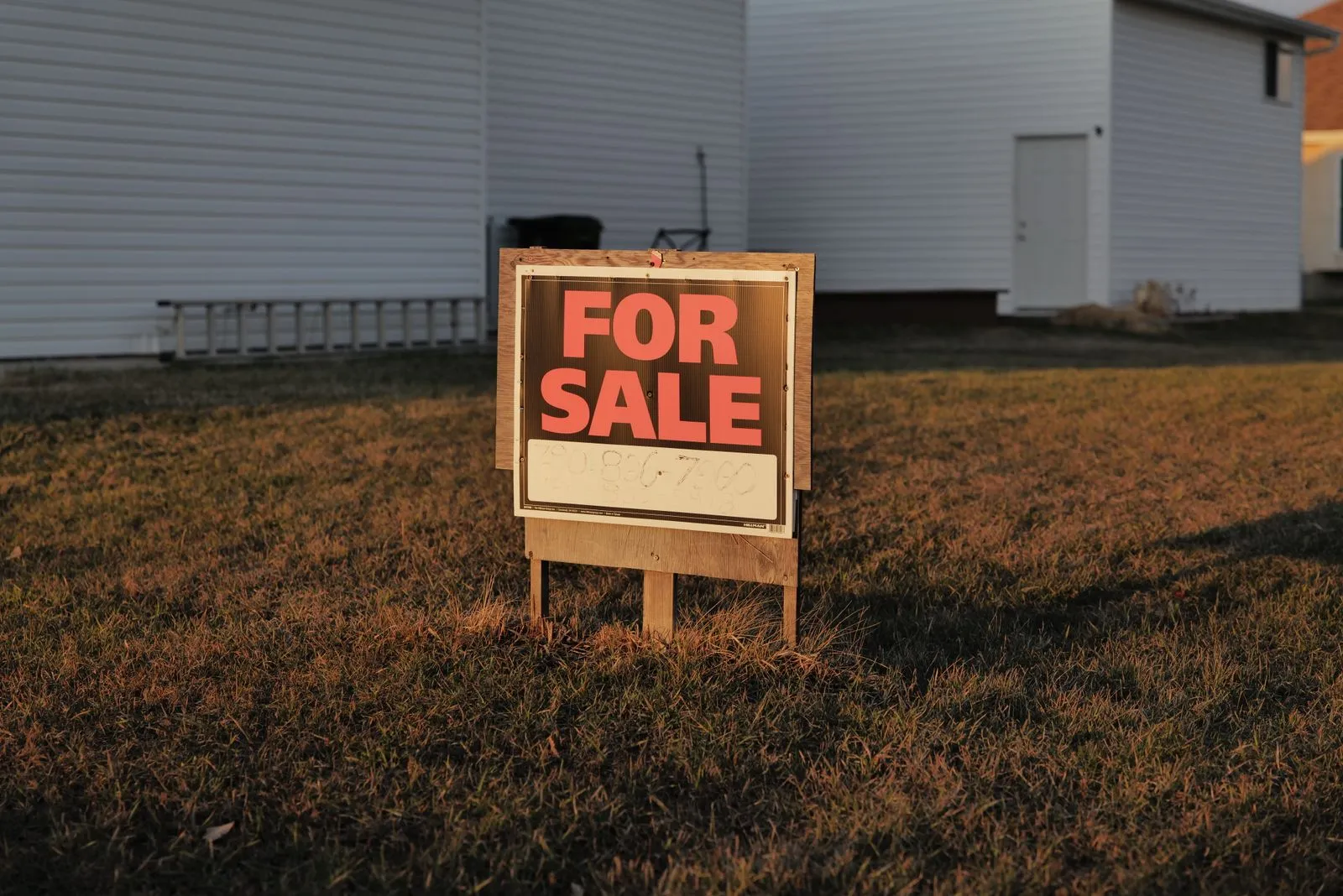 Red for-sale sign in the front yard of a suburban house