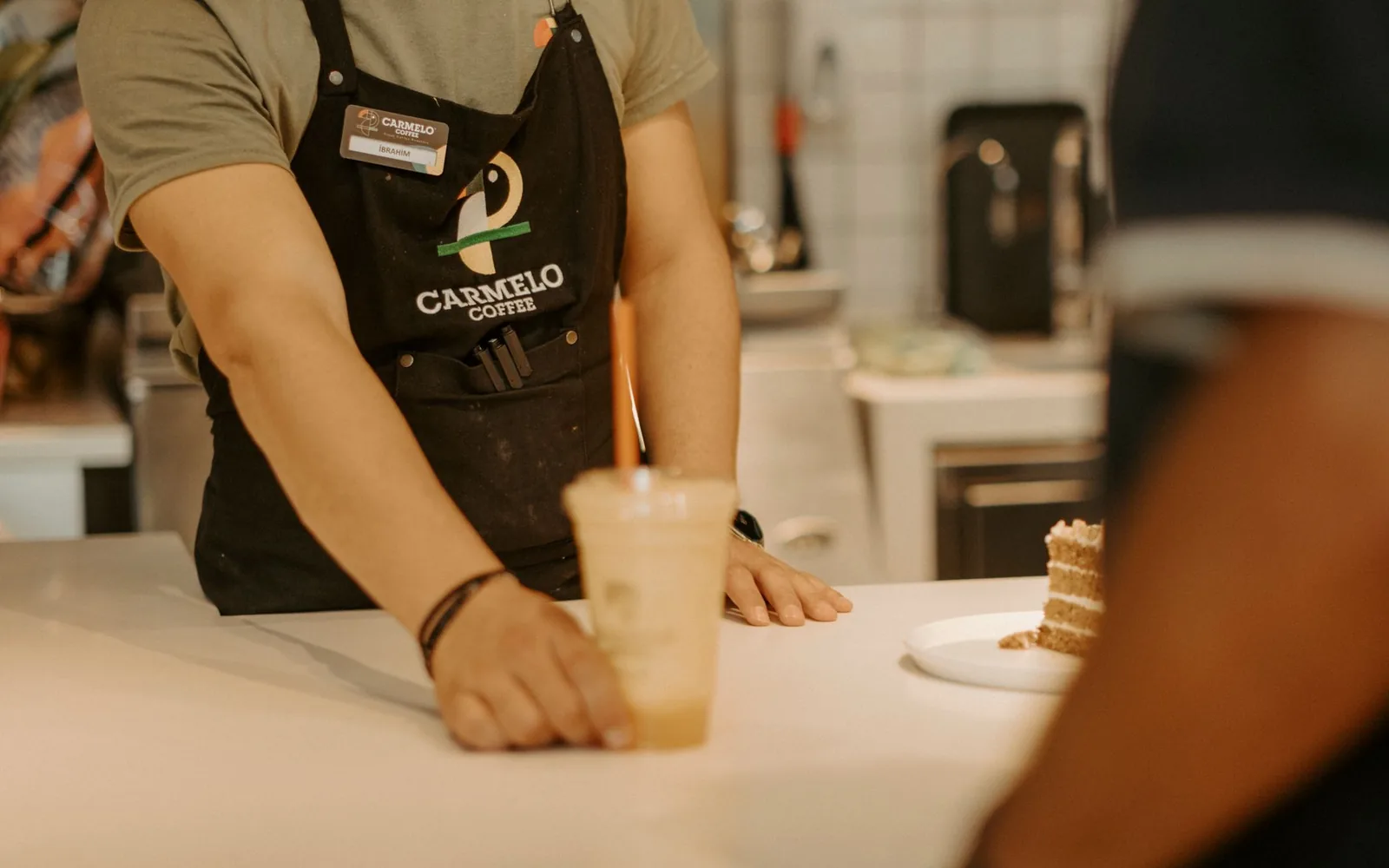 A barista handing a coffee across the counter at a cafe