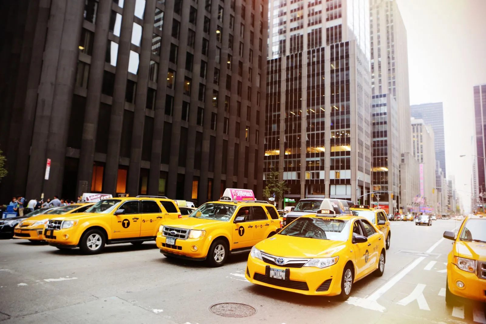Yellow taxis lined up on a busy New York City street scene
