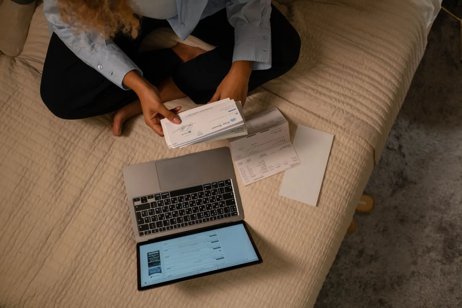 A person checking a bank statement with a laptop and coffee on a kitchen counter