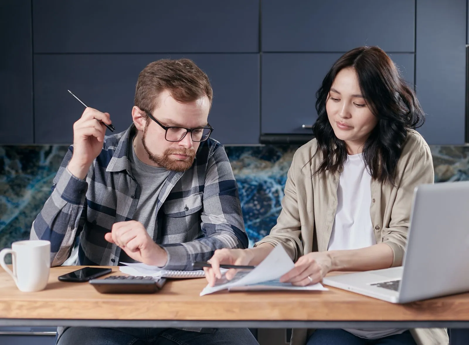 A couple at a desk reviewing paperwork with a calculator