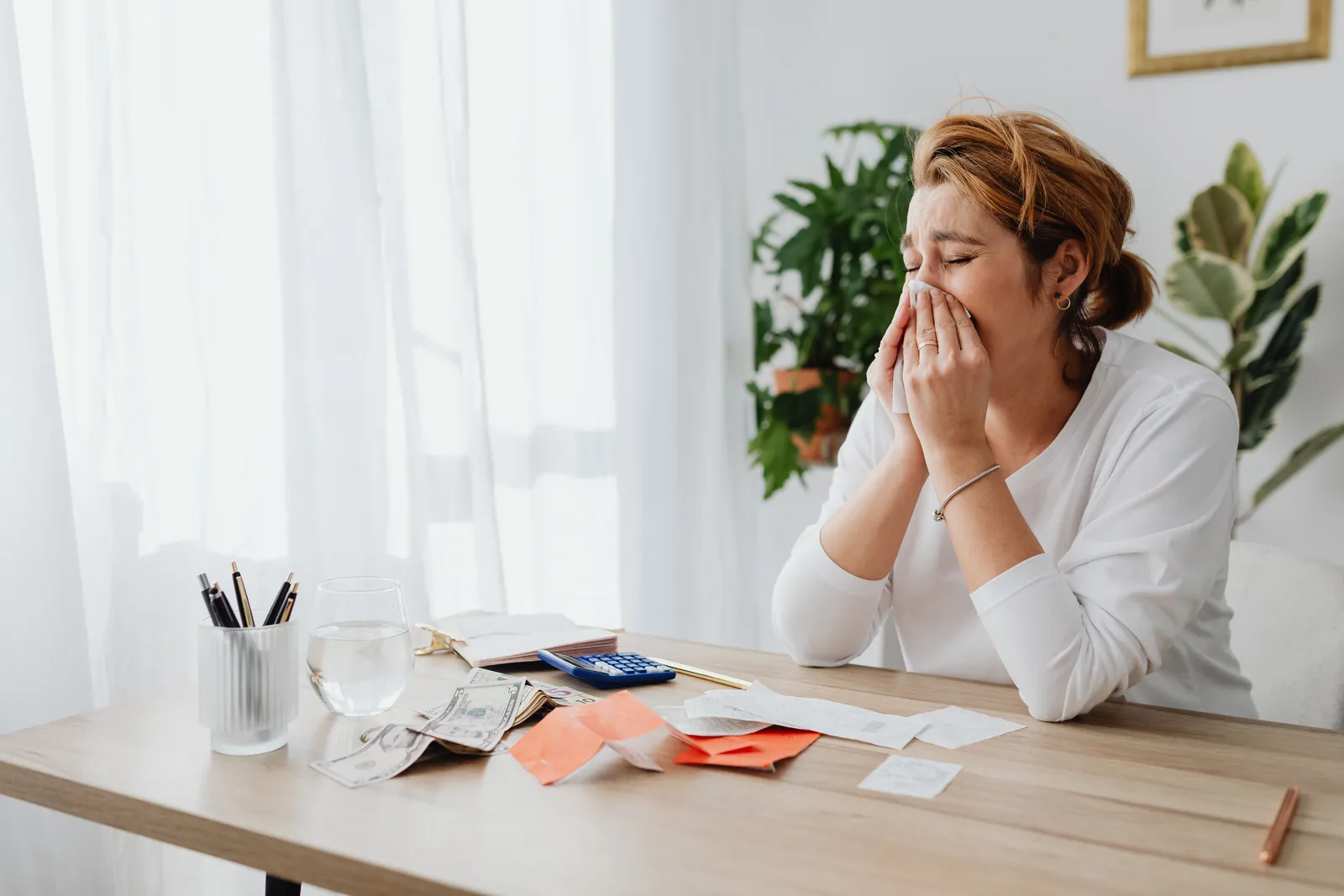 Woman reviewing paper bills and a laptop at a desk