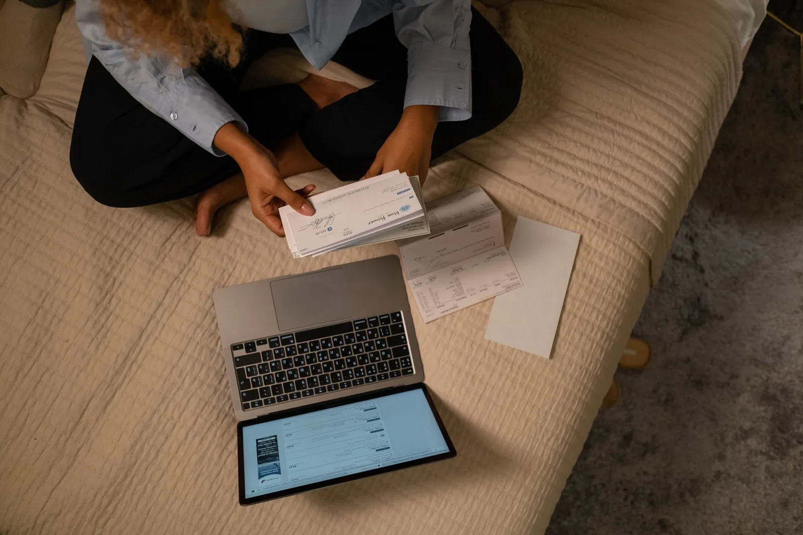 Person reviewing bills and a laptop at a desk at home