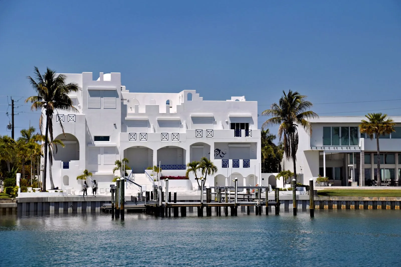 A coastal home with palm trees under a calm summer sky