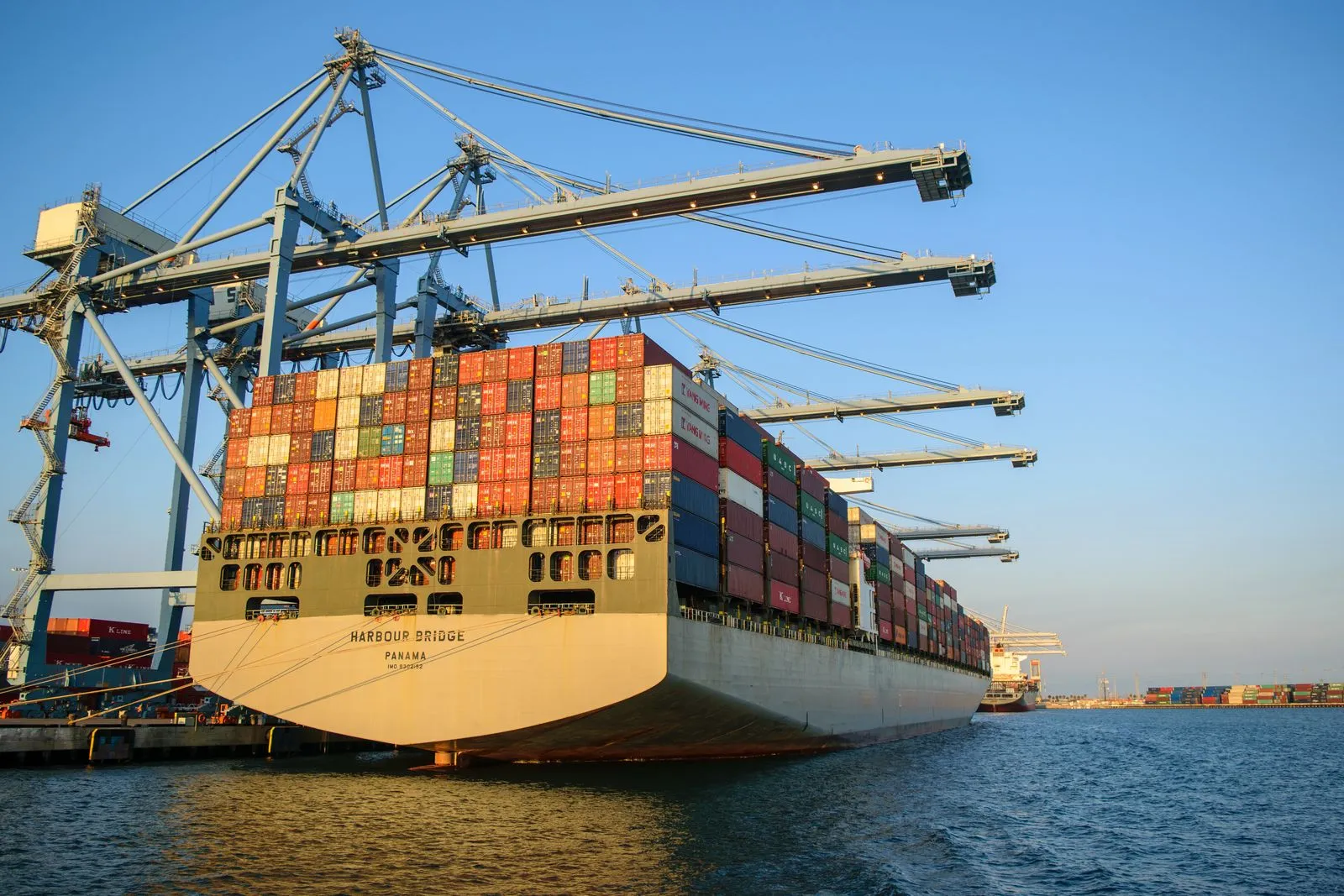 A container ship in harbor under a clear sky