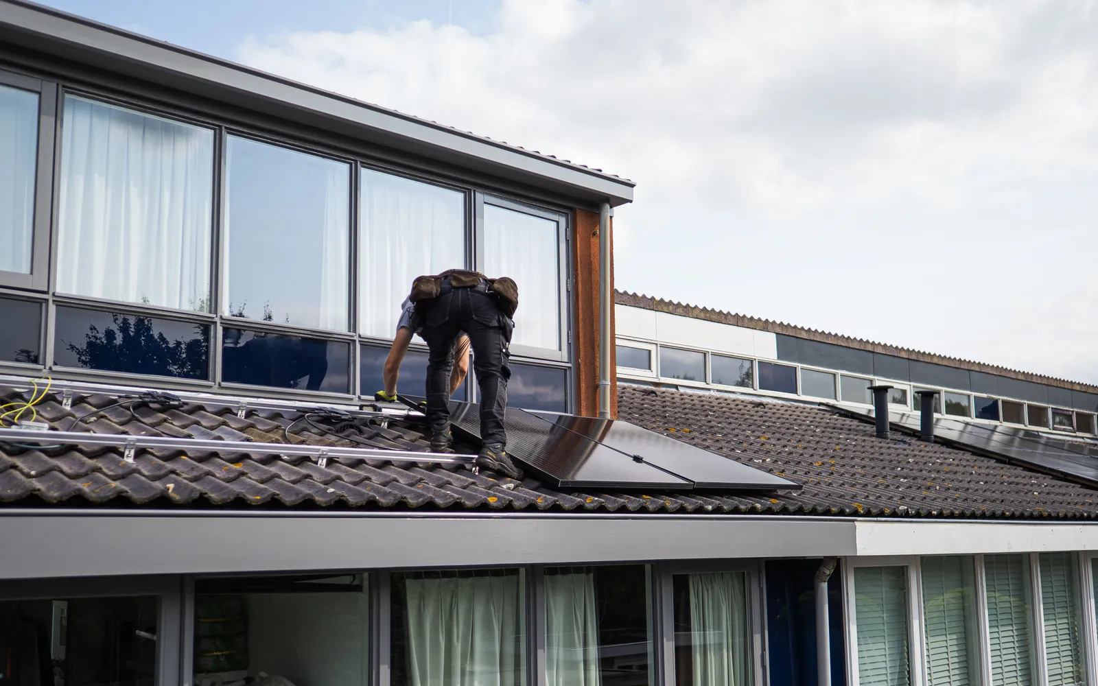 Installer placing a solar panel on a residential tiled roof