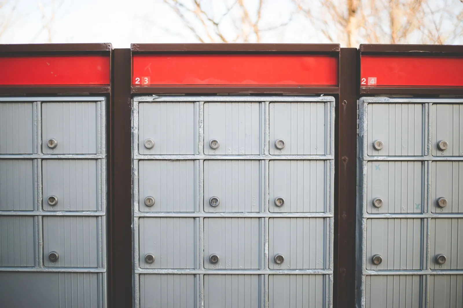 Row of gray outdoor community mailbox lockers with a red trim panel