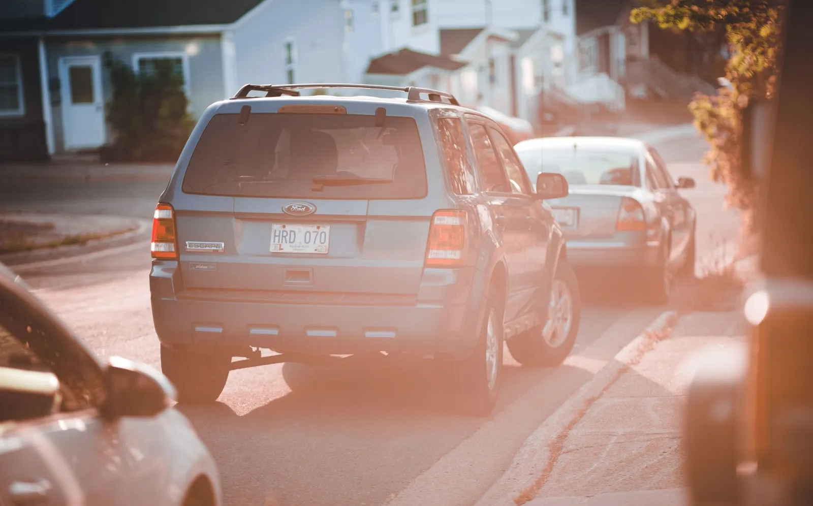 A blue SUV parked along a quiet residential street at sunset