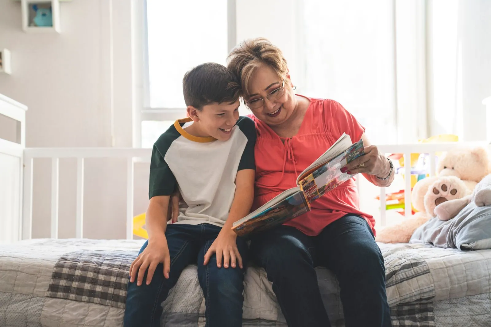 Grandmother helping a young child with a workbook at a kitchen table