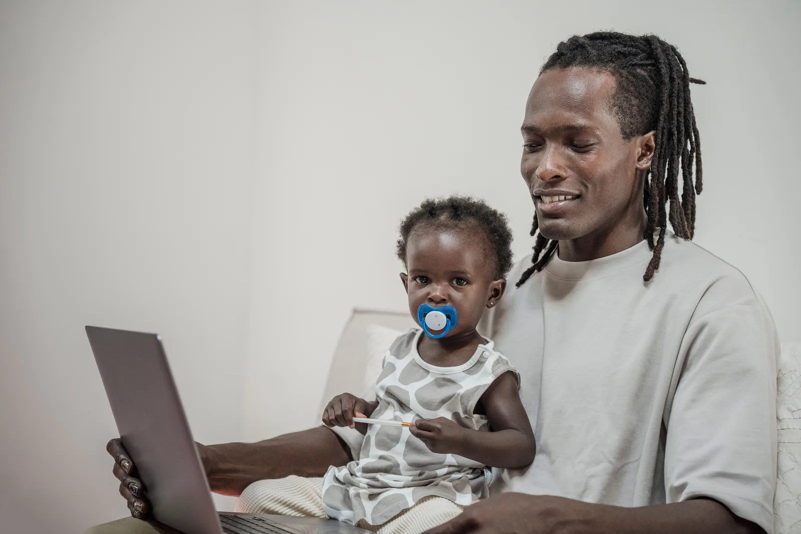 Parent holding a young child while looking at a laptop at home