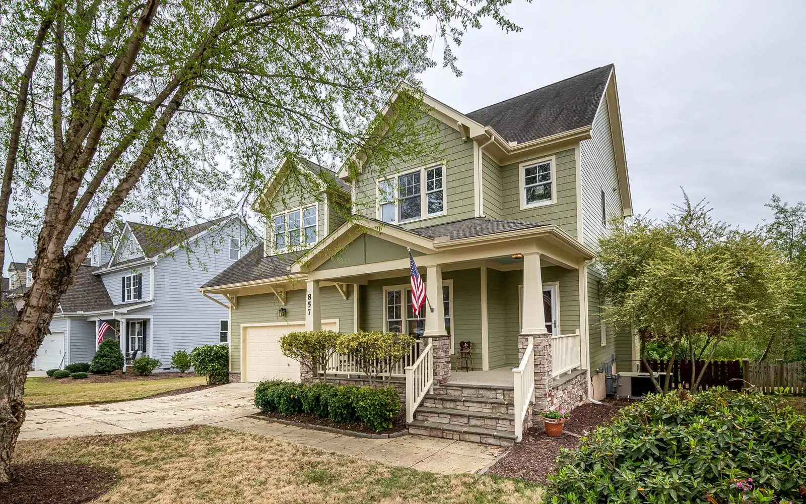 Green suburban house with an American flag hanging on the front porch