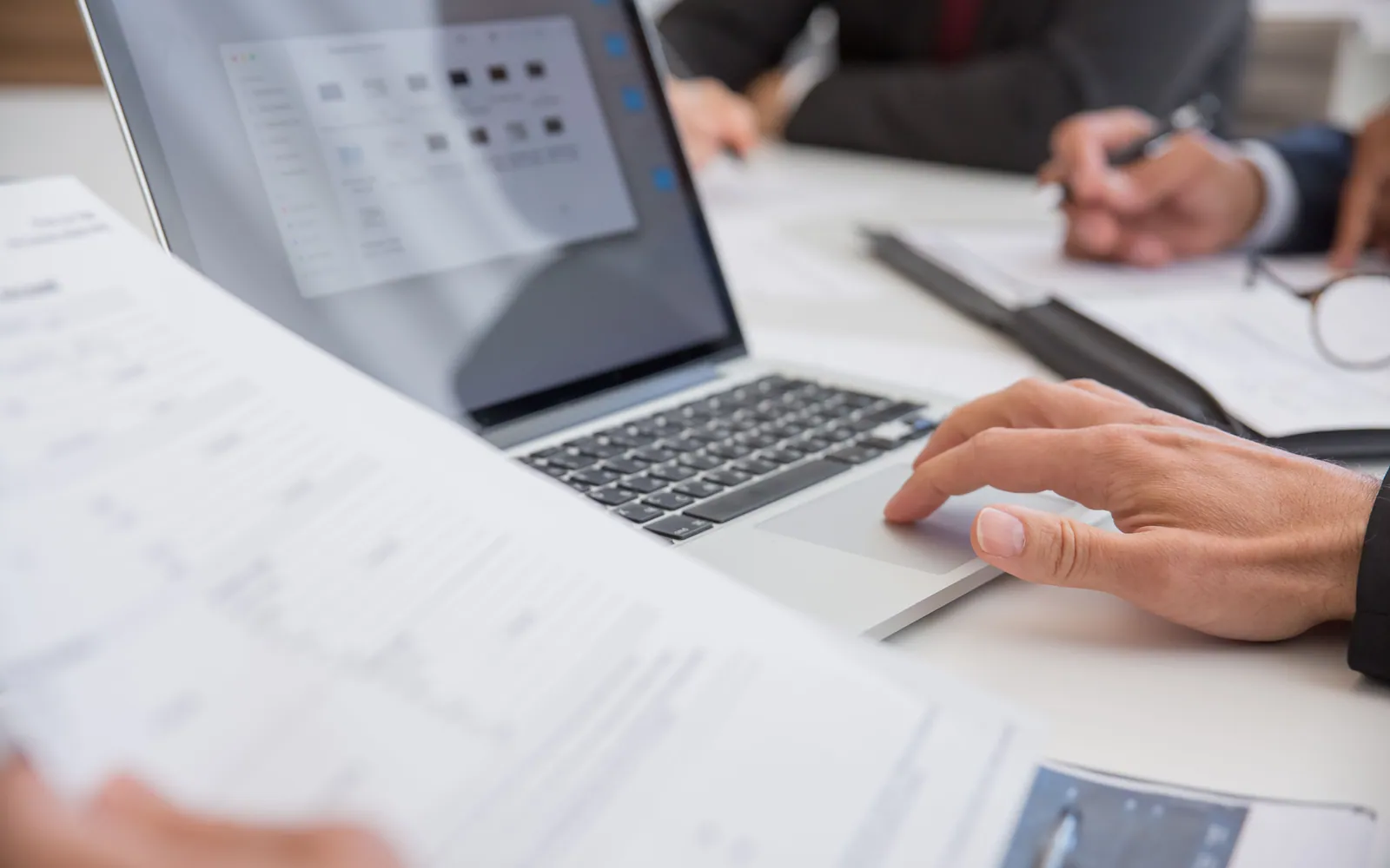 Person reviewing documents with a laptop